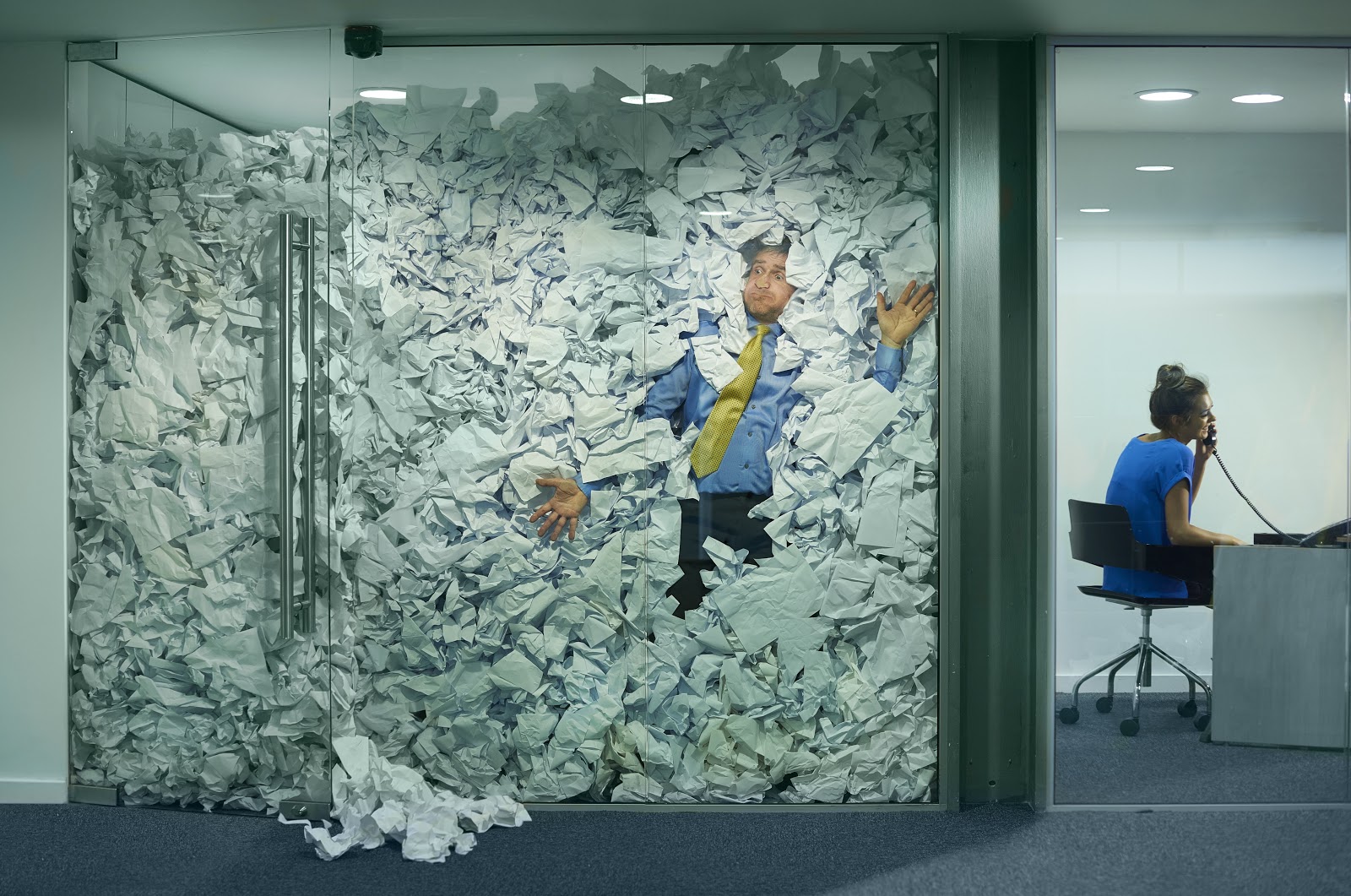 a man in an office with paper full to the ceiling