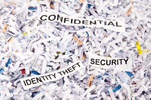 Image of shredded paper with pieces of paper that say "confidential" "identity theft" and "security"