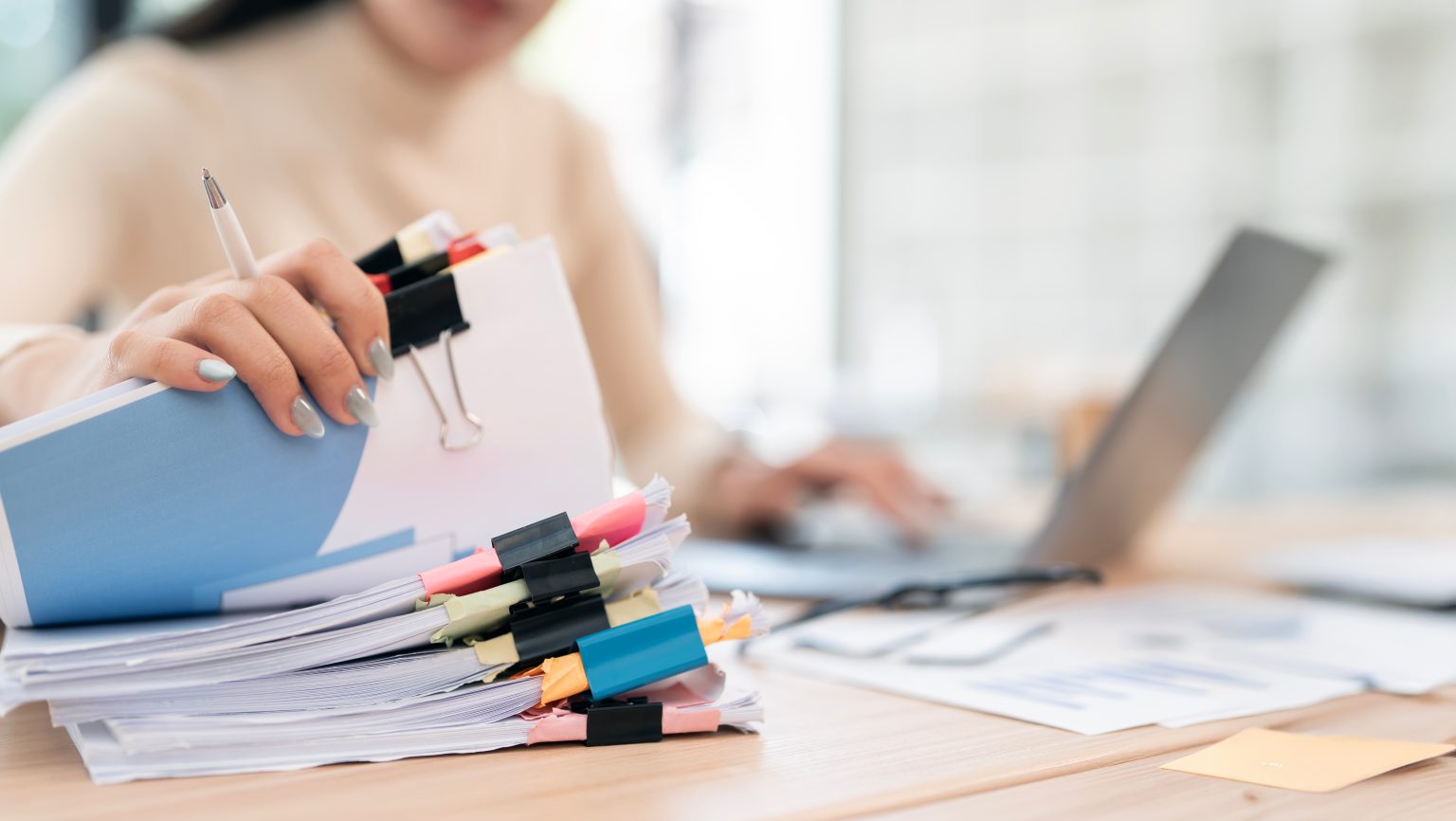 Businesswoman hands working in Stacks of paper files for searching and checking unfinished document achieves on folders papers.