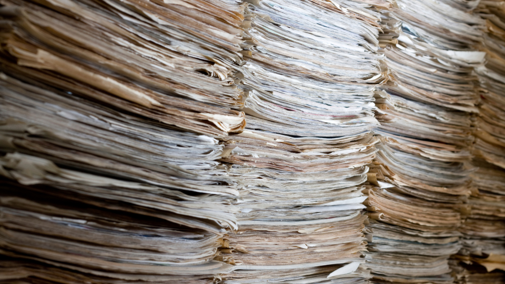 Large stacks of accumulated paper records ready for document shredding.